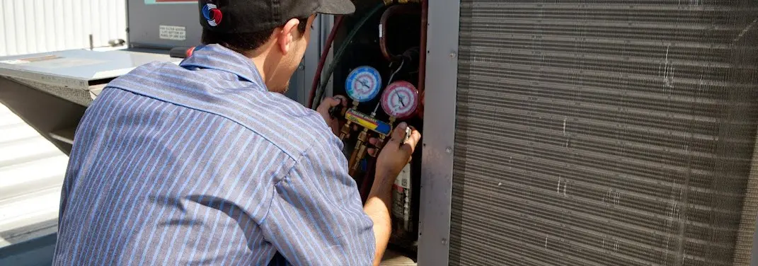 HVAC technician servicing a condenser unit in Fair Lakes
